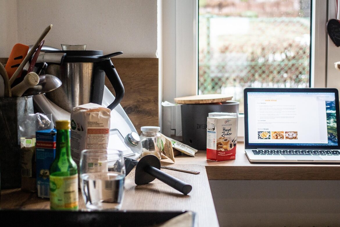 Aufgeräumte Küche mit frischen Zutaten, Schneidebrett und Laptop – Symbolbild für modernes Kochen.