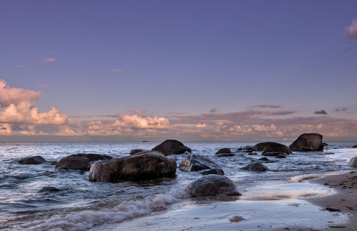 Große Felsen ragen aus dem klaren Wasser der Ostsee, umgeben von sanften Wellen unter einem leicht bewölkten Himmel.